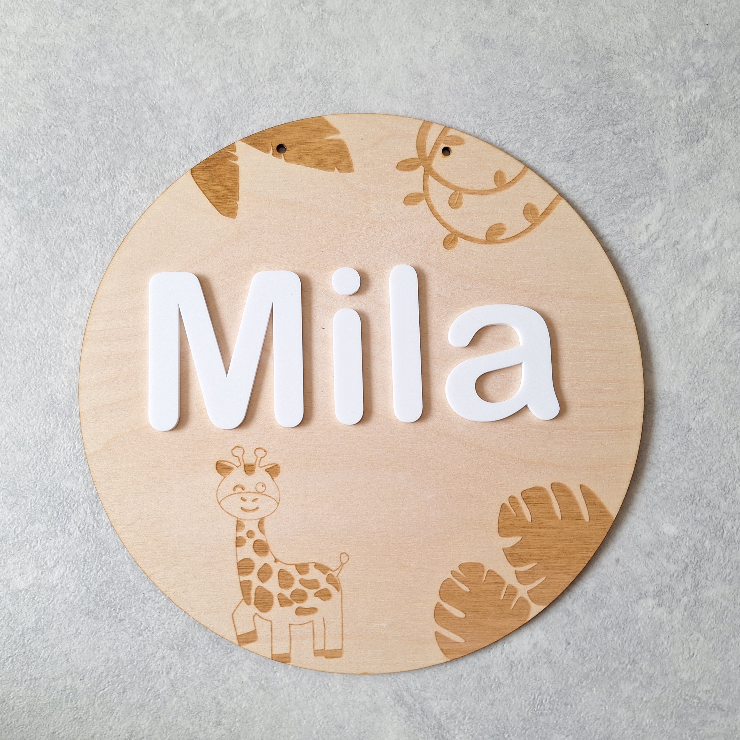 Rond houten bord met jungle thema erop gegraveerd met naam in strak lettertype erop geplakt